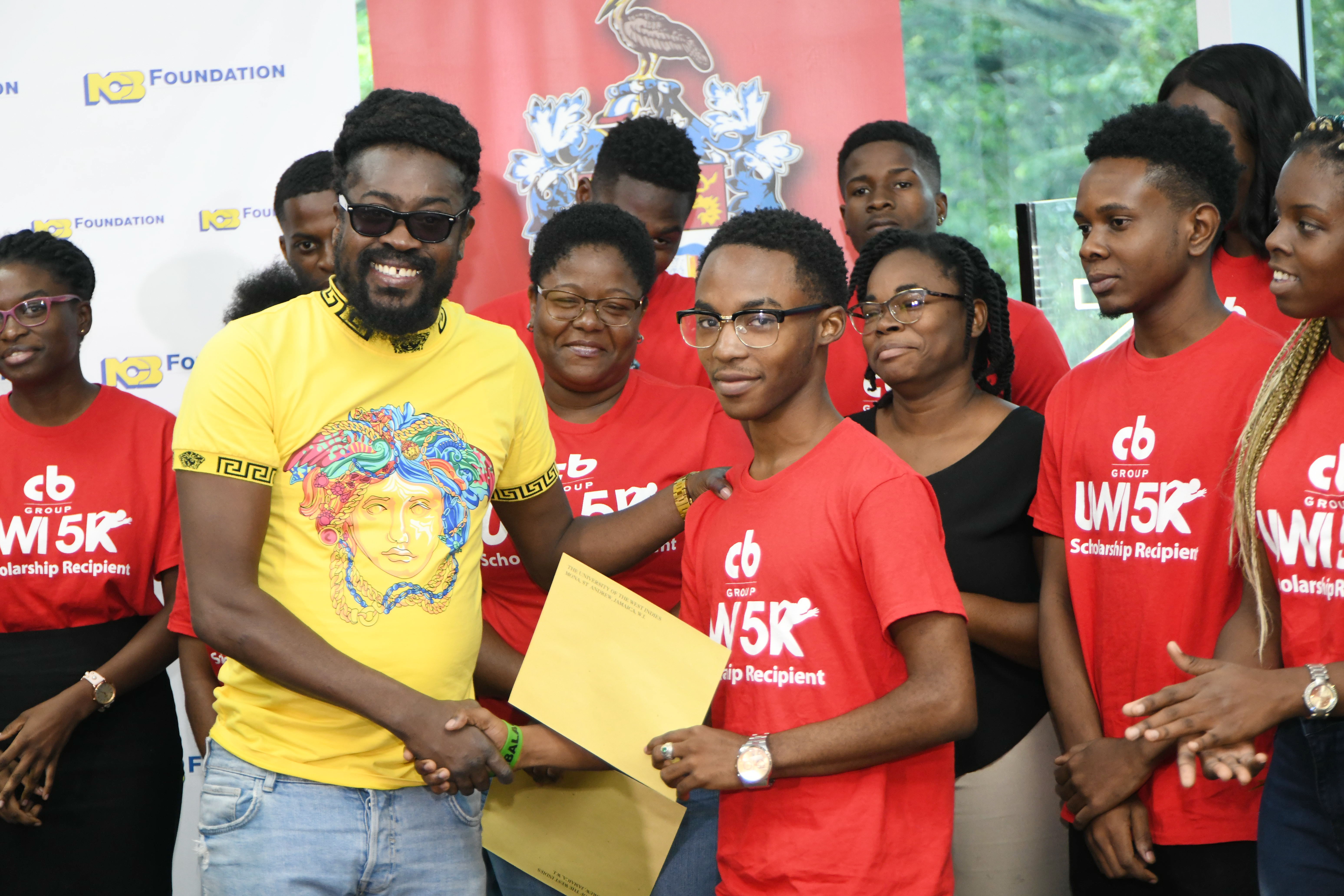 Jhevonte Webster receiving the CB Group UWI 5K/Khadene “Miss Kitty” Hylton Scholarship being presented on her behalf by Moses “Beenie Man” Davis. The presentation took place at the launch of the 5K fund raising event on October 2 at the UWI Regional Headquarters.